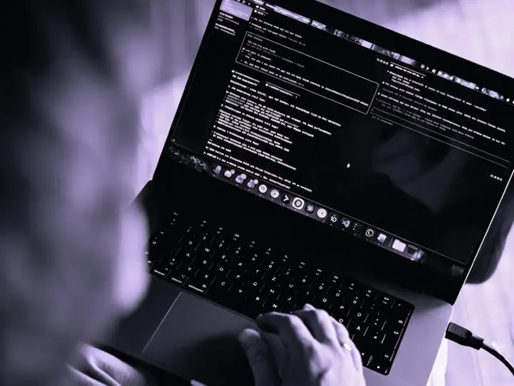 Blick über die Schulter auf einen Laptop mit Code